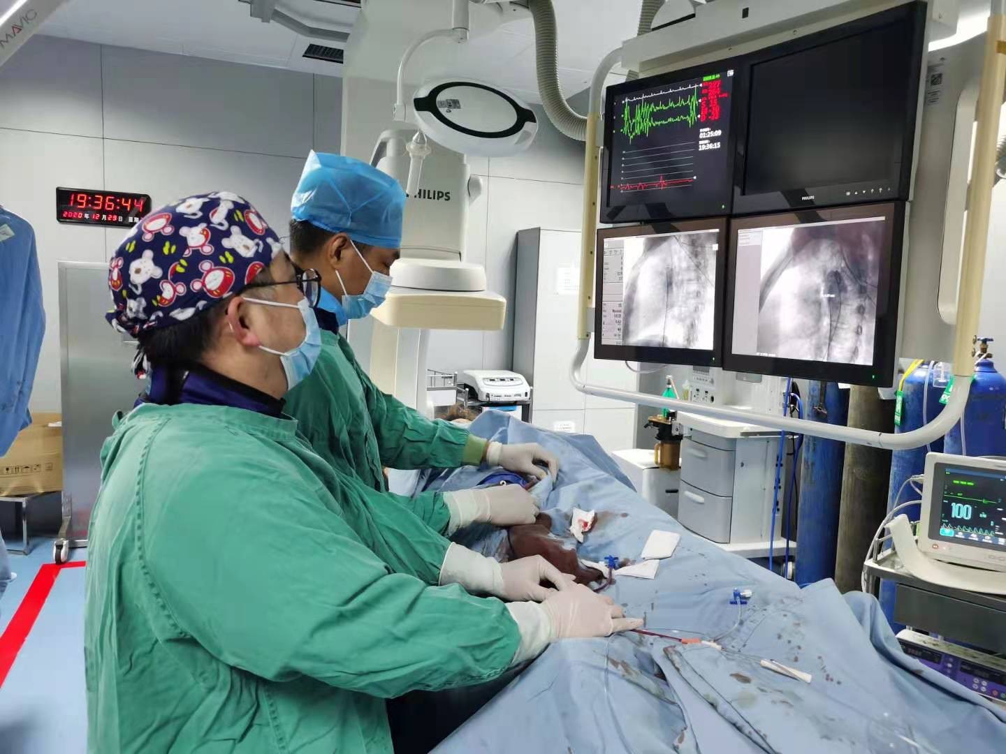 阳维德主任与副主任医师陈锋正在为石大姐施行先心病封堵术