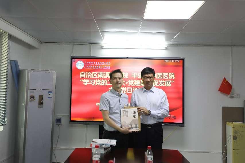 5.南溪山医院党委书记戴前富（右）向平乐县中医医院党总支部书记陶驰茂赠送医院文化丛书。李金戈摄