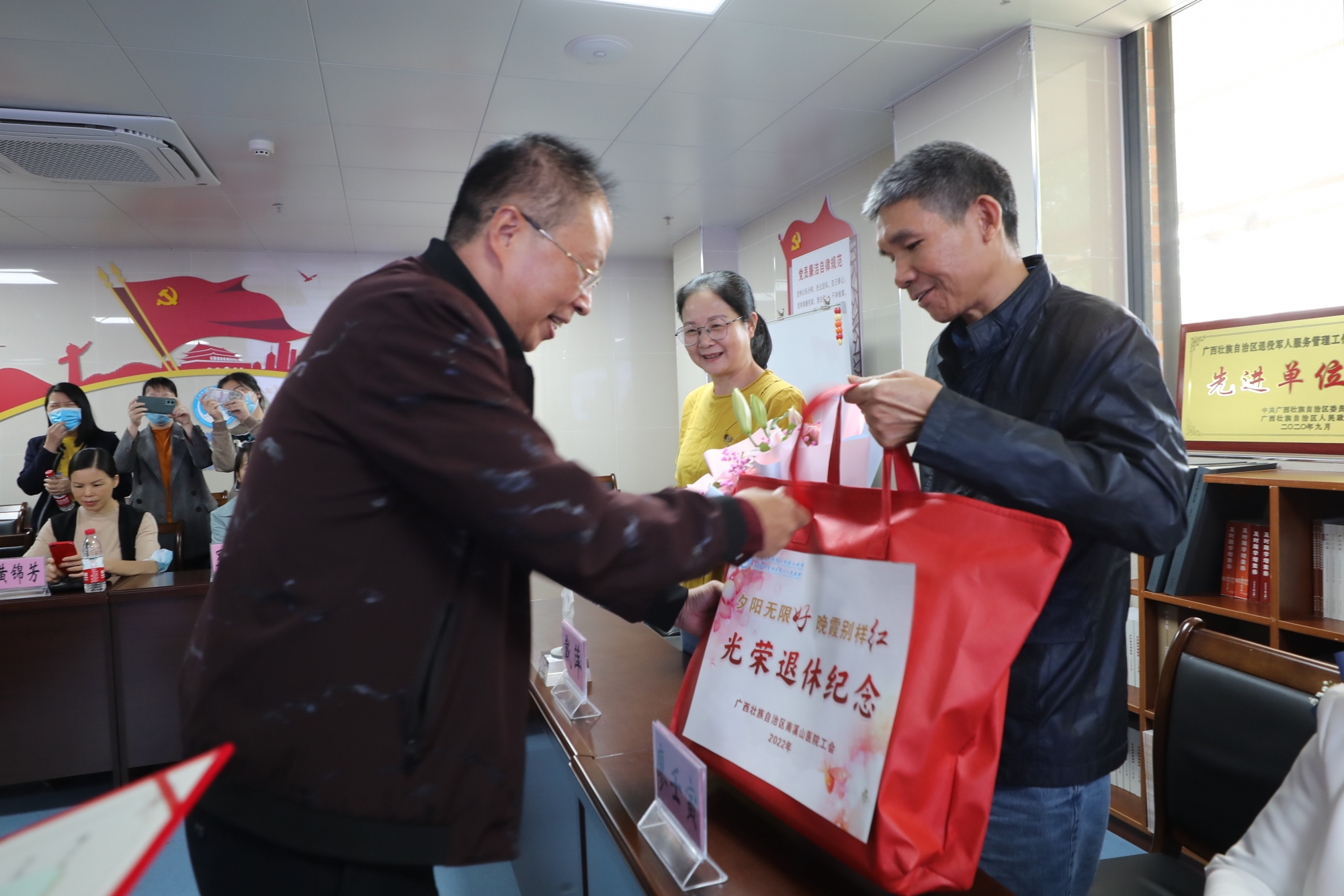 医院党委书记、工会主席张超群向光荣退休职工送上纪念品 伍家琪 摄